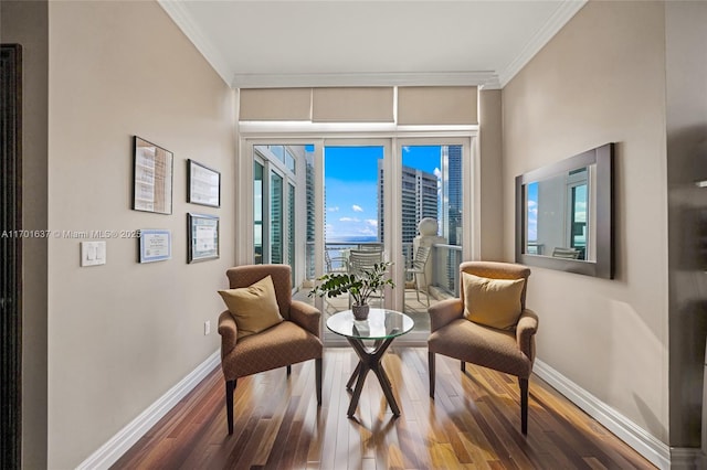 living area with ornamental molding, wood finished floors, and baseboards