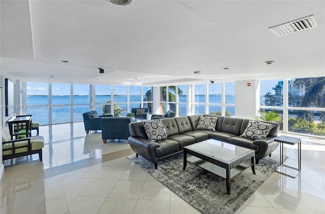 living room with a wall of windows, visible vents, a water view, and light tile patterned flooring