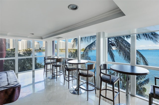 sunroom / solarium with a raised ceiling and a water view