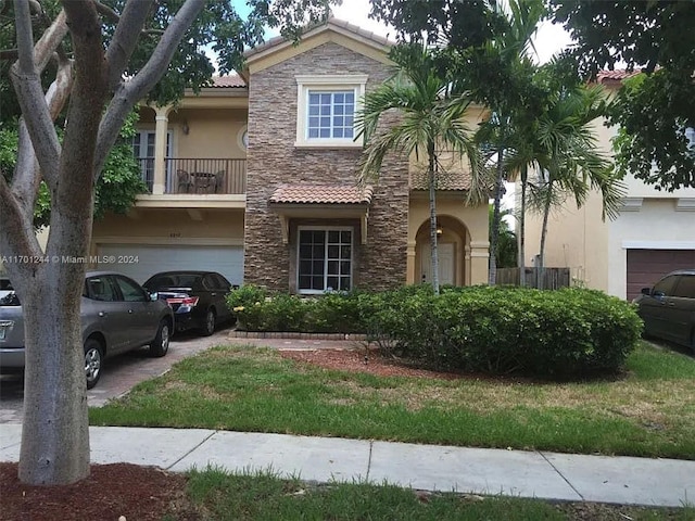 8859 SW 223rd Ter, Cutler Bay, FL 33190 - view of front of home with stucco siding, stone siding, a tile roof, a garage, and a balcony