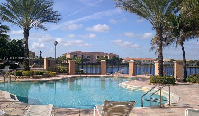 view of pool featuring a water view and a patio