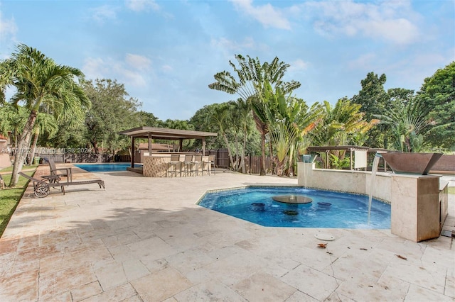 view of pool featuring exterior bar, pool water feature, and a patio area