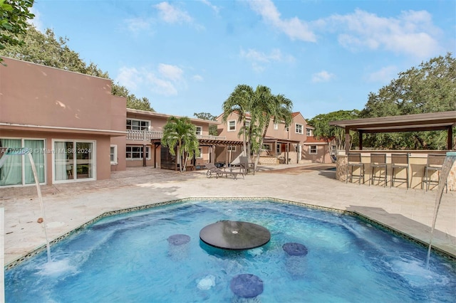 view of pool featuring exterior bar and a patio