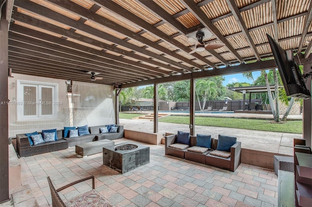 view of patio / terrace with ceiling fan, a fenced in pool, and an outdoor living space with a fire pit