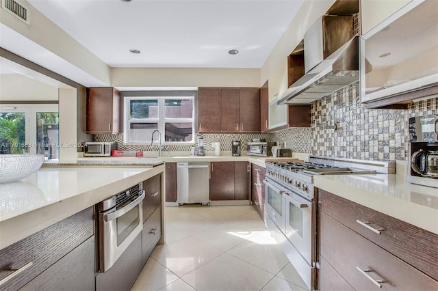 kitchen featuring appliances with stainless steel finishes, tasteful backsplash, plenty of natural light, and wall chimney range hood