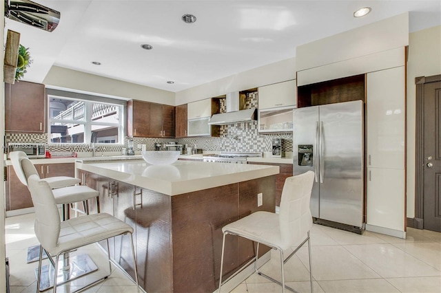 kitchen with backsplash, a kitchen island, a kitchen bar, and appliances with stainless steel finishes