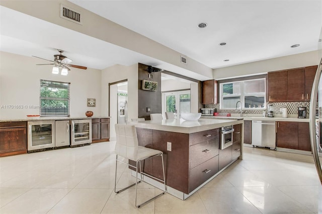 kitchen with stainless steel appliances, a wealth of natural light, a center island, and beverage cooler