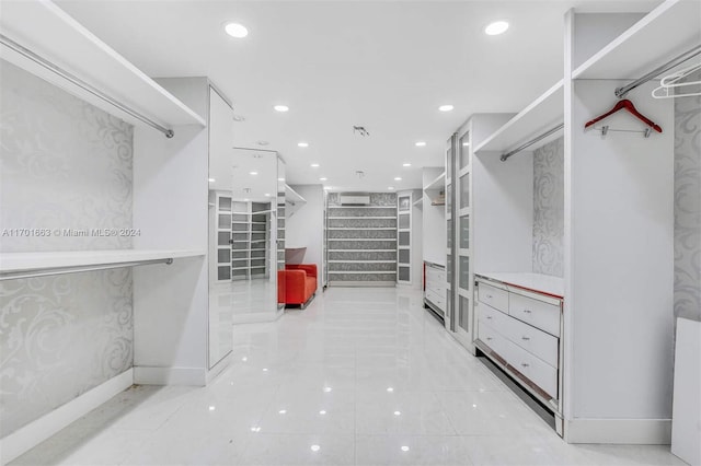 walk in closet with a wall mounted air conditioner and light tile patterned flooring