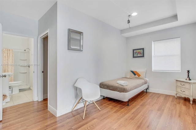 bedroom featuring light wood-type flooring and ensuite bath