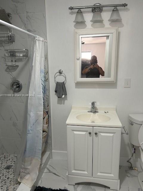 bathroom featuring toilet, vanity, and walk in shower