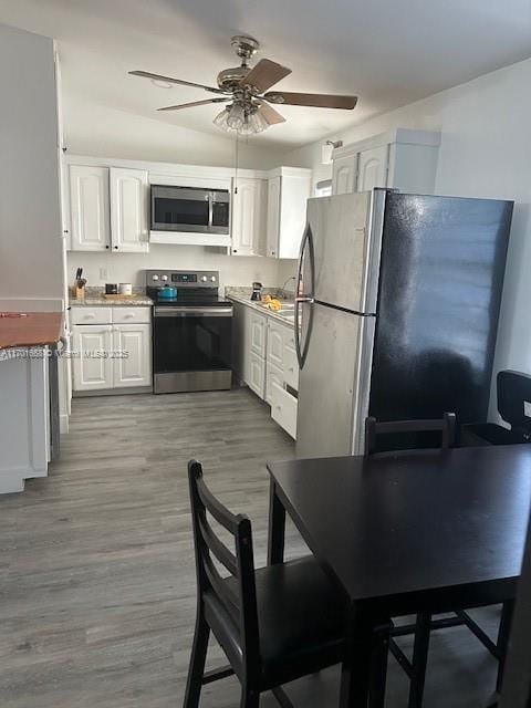 kitchen with ceiling fan, white cabinets, stainless steel appliances, and light hardwood / wood-style floors