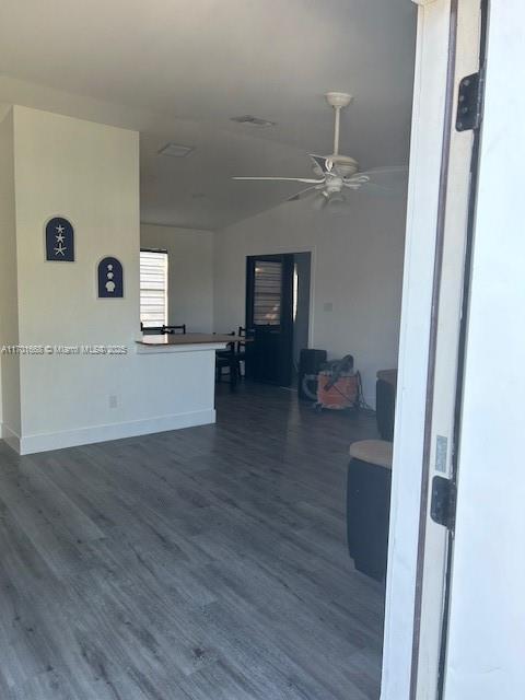 living room featuring ceiling fan, dark wood-type flooring, and vaulted ceiling