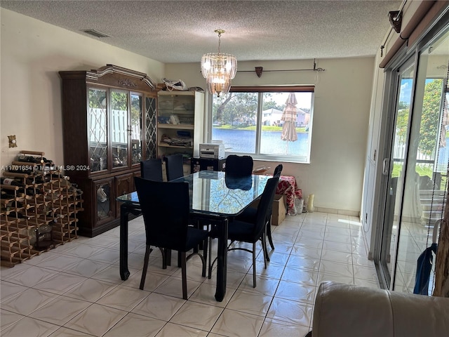 tiled dining room featuring a healthy amount of sunlight, a water view, and a textured ceiling