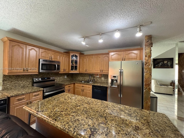 kitchen featuring stone counters, decorative backsplash, stainless steel appliances, and a textured ceiling