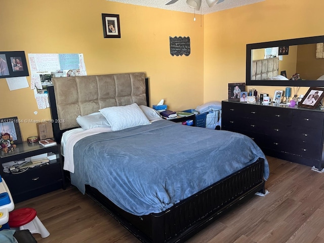 bedroom featuring dark hardwood / wood-style floors, ceiling fan, and a textured ceiling