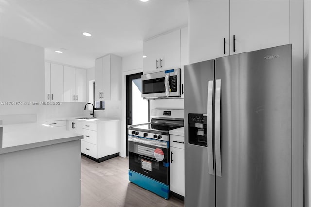 kitchen featuring hardwood / wood-style flooring, sink, white cabinetry, and stainless steel appliances