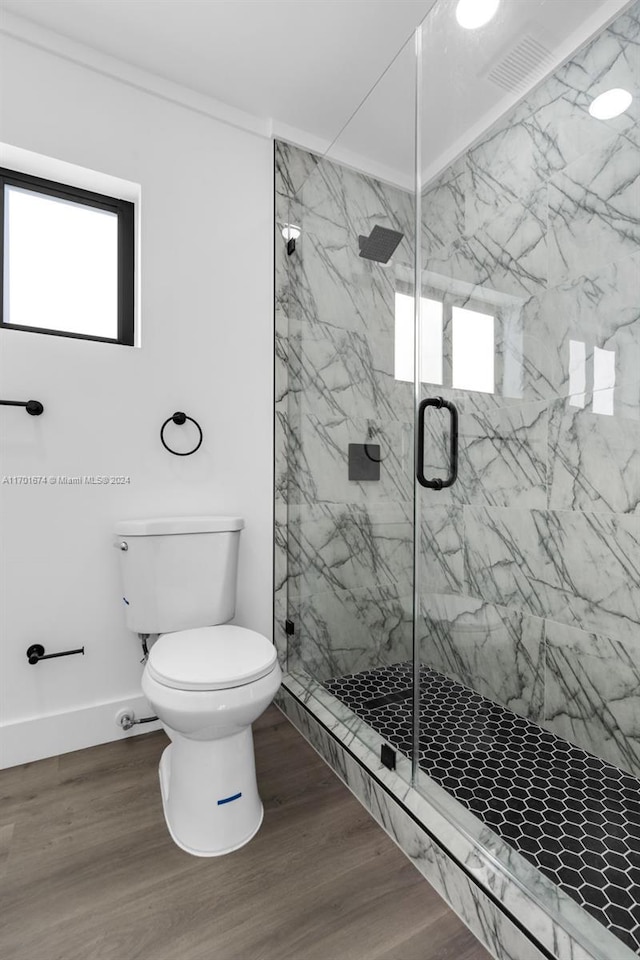 bathroom with wood-type flooring, a shower with shower door, and toilet