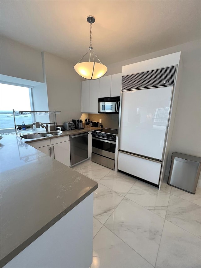 kitchen with dark stone counters, sink, decorative light fixtures, white cabinetry, and stainless steel appliances