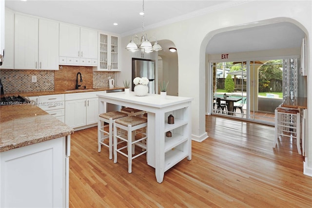 kitchen featuring light stone countertops, decorative light fixtures, light hardwood / wood-style floors, white cabinetry, and stainless steel appliances