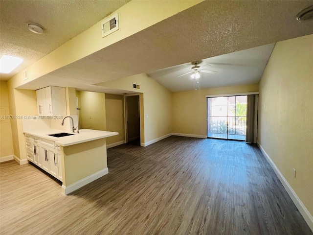 kitchen featuring sink, a textured ceiling, hardwood / wood-style flooring, ceiling fan, and white cabinets