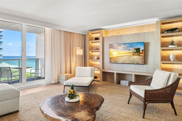 sitting room featuring built in features, a water view, and hardwood / wood-style flooring