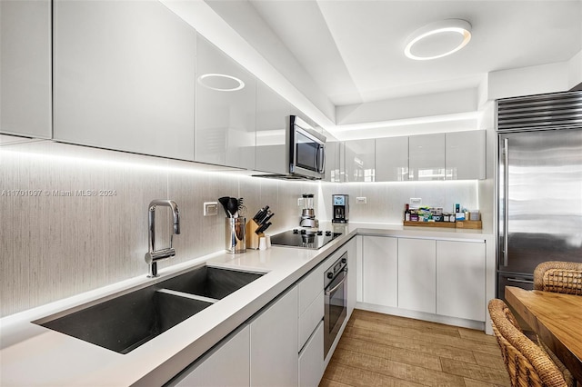 kitchen featuring white cabinetry, sink, stainless steel appliances, and light hardwood / wood-style floors