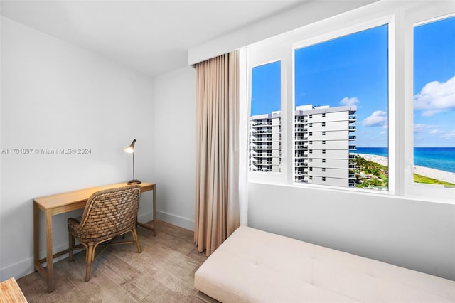 bedroom featuring a view of the beach, hardwood / wood-style floors, and a water view