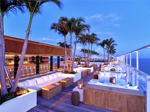 deck at dusk featuring outdoor lounge area and a water view