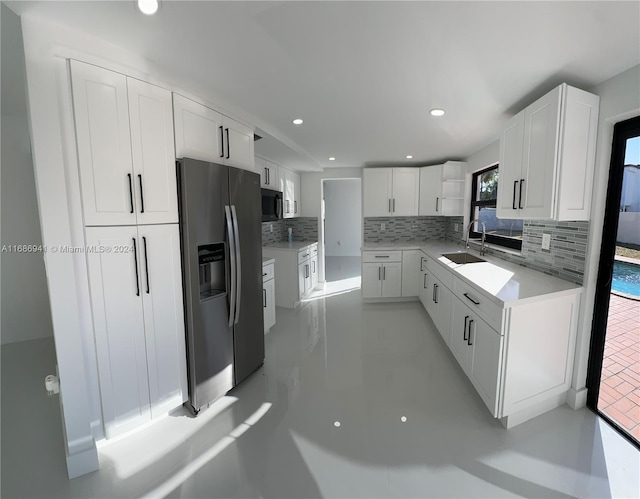 kitchen featuring decorative backsplash, sink, white cabinets, and appliances with stainless steel finishes