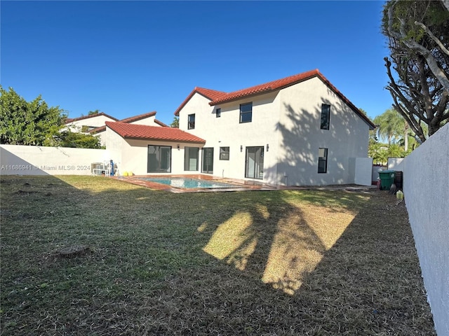 back of property featuring a yard and a fenced in pool