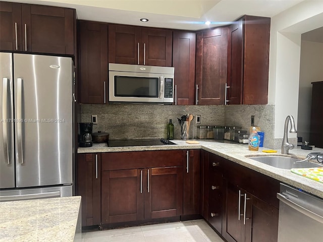 kitchen featuring backsplash, light stone counters, sink, and appliances with stainless steel finishes