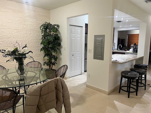 dining room featuring electric panel, sink, and light tile patterned flooring