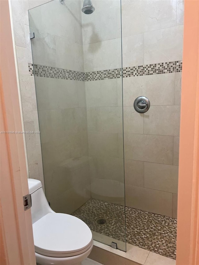 bathroom featuring tiled shower and toilet