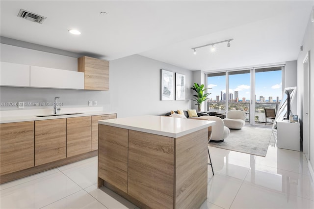 kitchen with a center island, sink, light tile patterned floors, expansive windows, and white cabinets