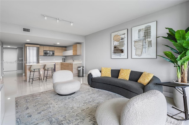 living room with light tile patterned flooring, sink, and rail lighting