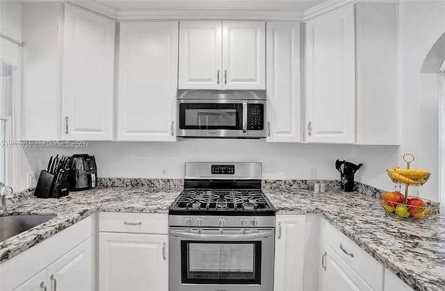 1640 Jefferson St, Hollywood, FL 33020 - kitchen with appliances with stainless steel finishes, white cabinetry, a sink, and arched walkways