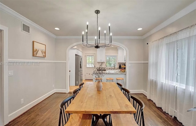 dining space with a chandelier, ornamental molding, and light hardwood / wood-style flooring