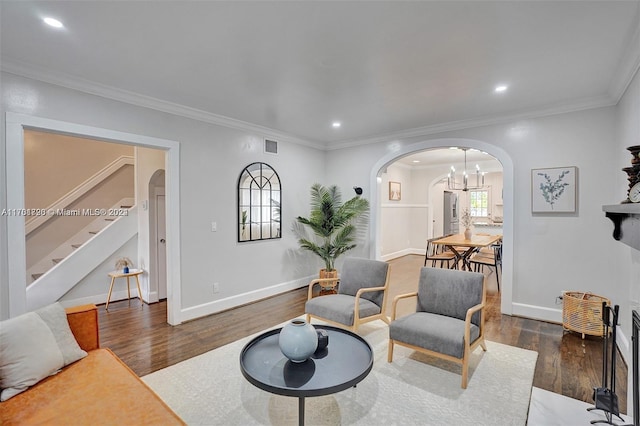 living room featuring a notable chandelier, dark hardwood / wood-style flooring, and ornamental molding