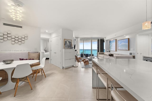 kitchen with light stone counters, expansive windows, light tile patterned floors, a water view, and hanging light fixtures