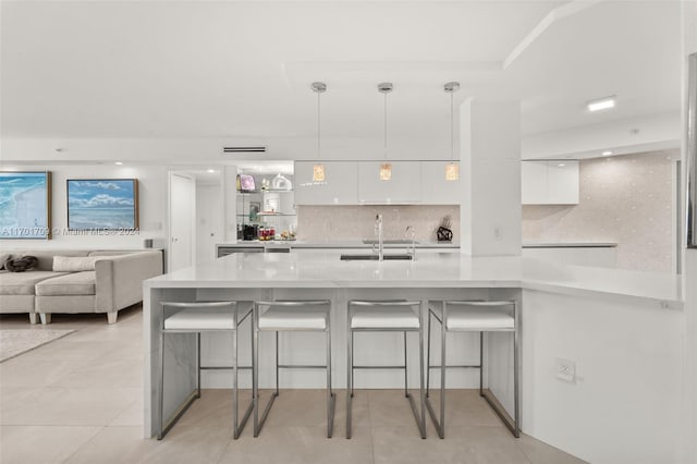 kitchen featuring pendant lighting, sink, white cabinetry, kitchen peninsula, and a breakfast bar area