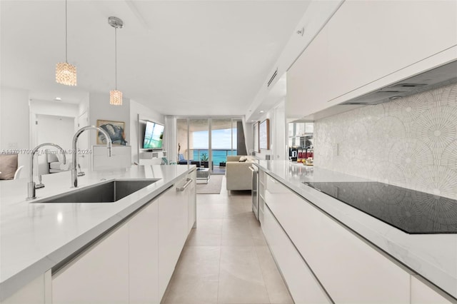 kitchen featuring sink, backsplash, decorative light fixtures, black electric cooktop, and white cabinets