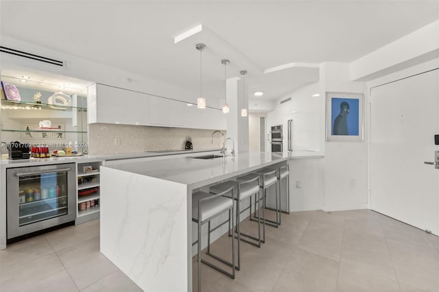 kitchen featuring white cabinets, sink, hanging light fixtures, wine cooler, and light stone countertops