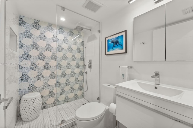 bathroom with tiled shower, vanity, and toilet