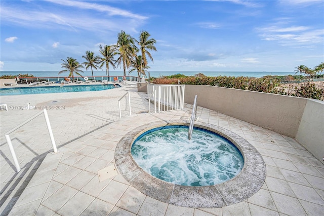 view of pool with a water view, a hot tub, and a patio area