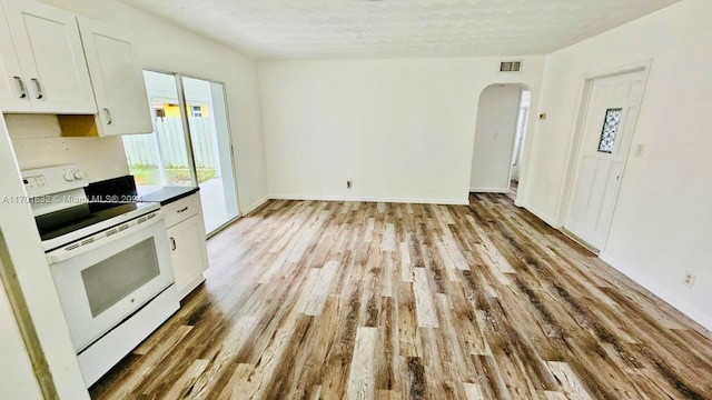 kitchen with white cabinets, a textured ceiling, light wood-type flooring, and white electric stove