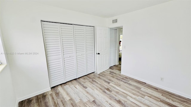 unfurnished bedroom with light wood-type flooring and a closet