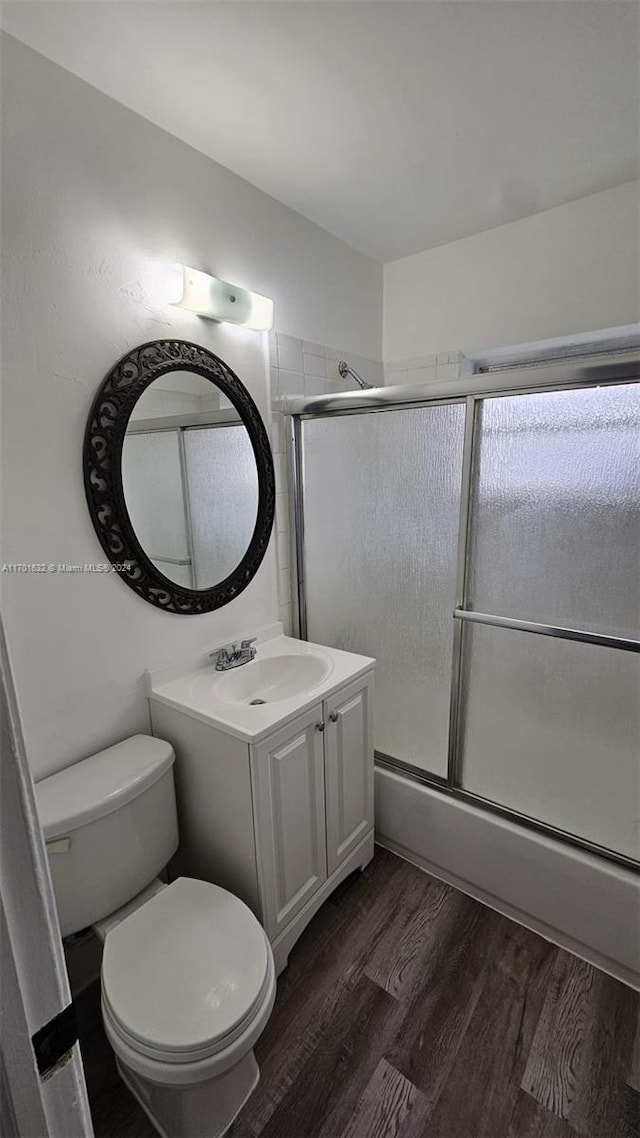 full bathroom with wood-type flooring, vanity, toilet, and enclosed tub / shower combo