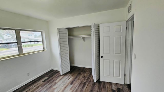 unfurnished bedroom with dark hardwood / wood-style flooring and a closet