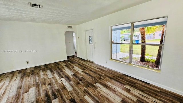 unfurnished room with dark wood-type flooring and a textured ceiling