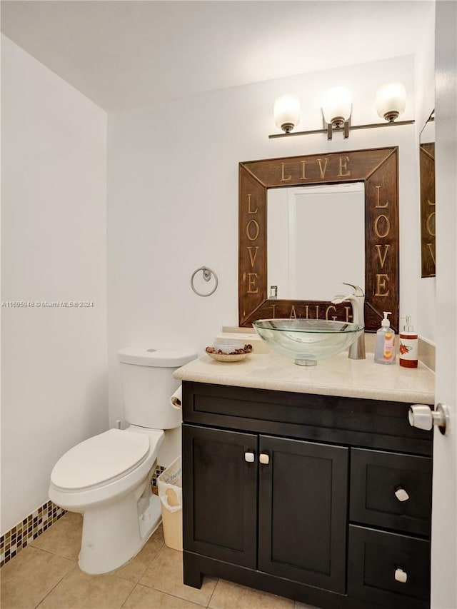 bathroom with toilet, vanity, and tile patterned floors